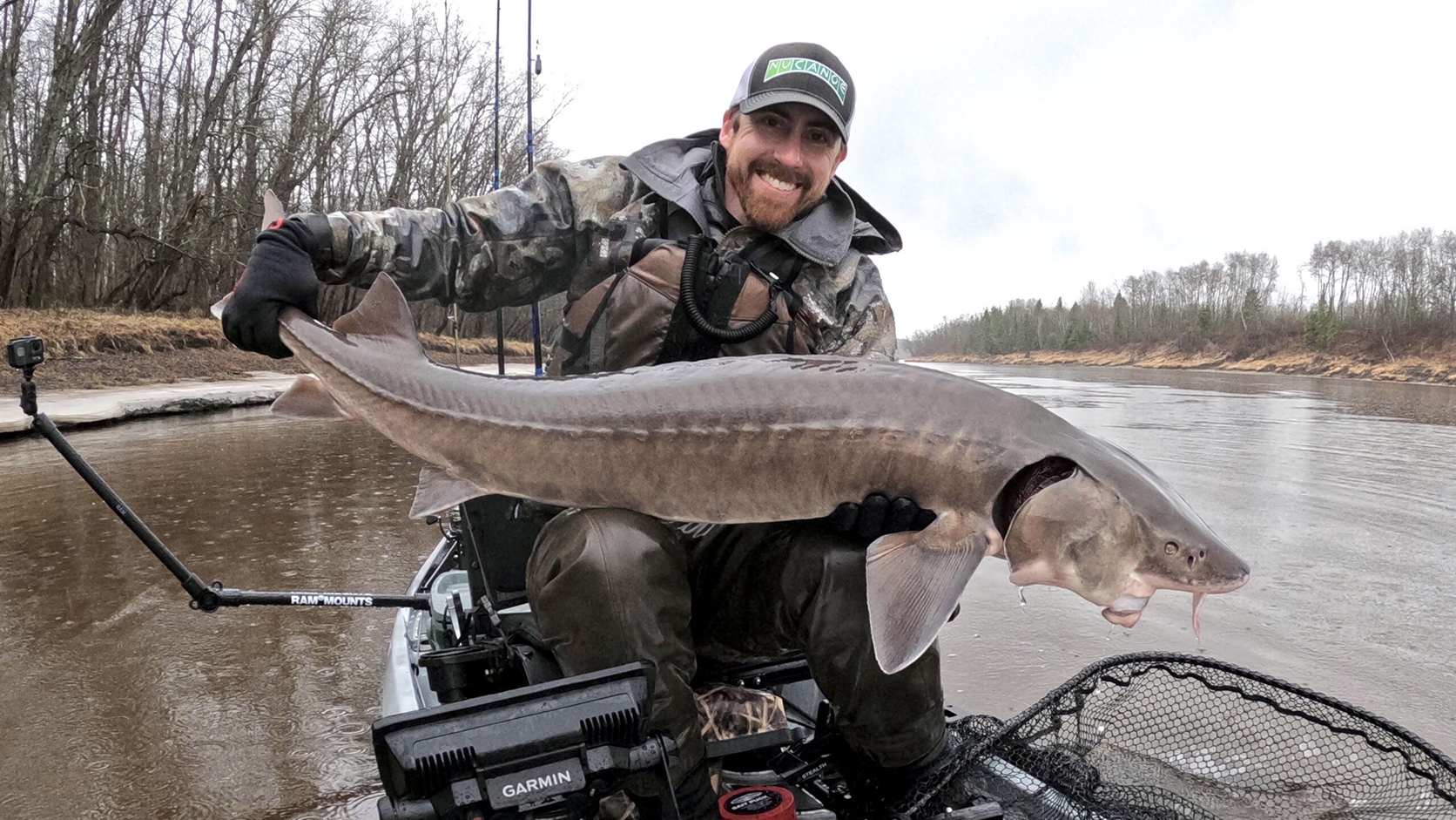 Man kayak fishing holding a Sturgeon